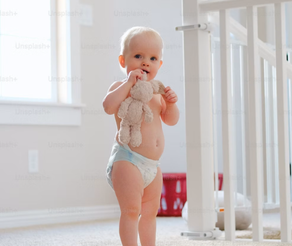 A baby standing beside a cot